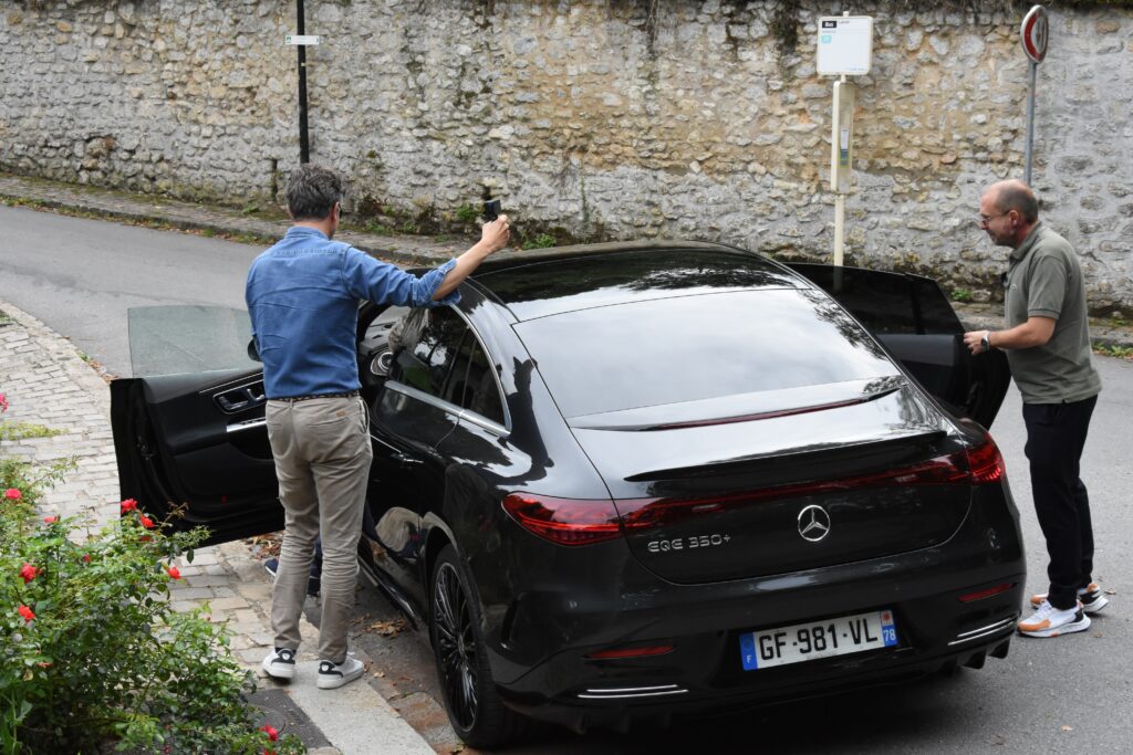 Vue arrière de la Mercedes EQE avec Vincent et Cédric montant à bord 